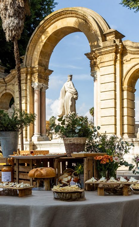Buffet de cóctel junto a un arco histórico con estatua en el Parque de María Luisa