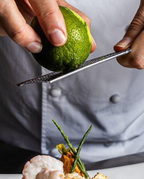 Cocinero terminando un plato con ralladura de lima