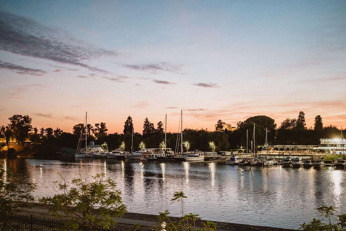 Puerto deportivo sobre el Guadalquivir al atardecer, con los barcos iluminados