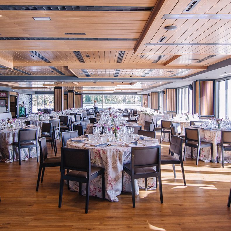 Salón con techo de madera y mesas redondas preparadas