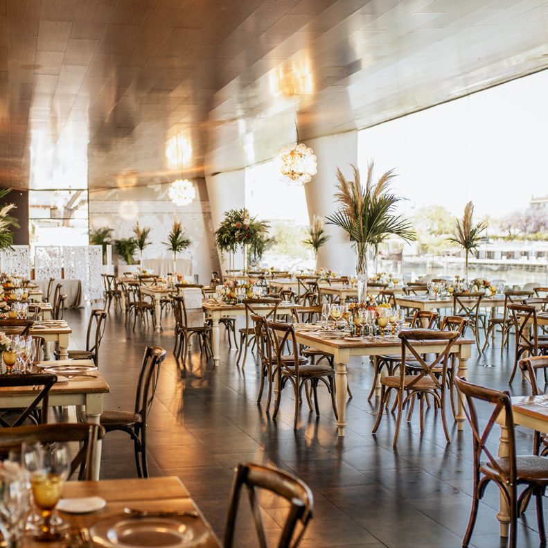 Salón con mesas de madera y vistas al río