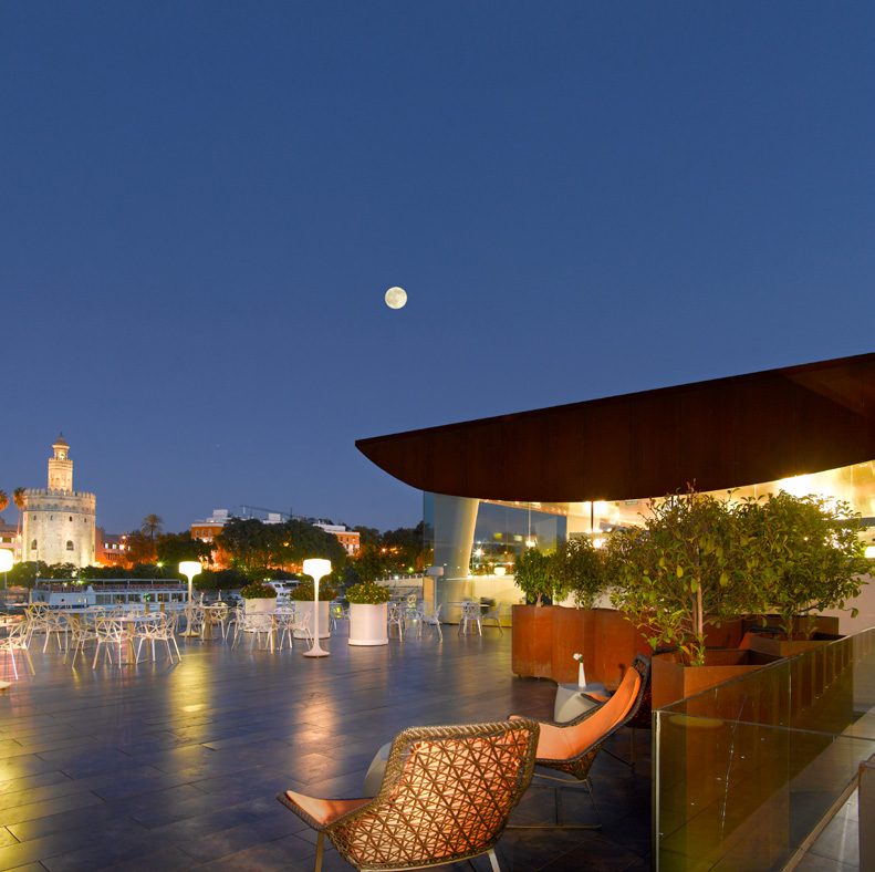 Terraza de noche con la Torre del Oro iluminada
