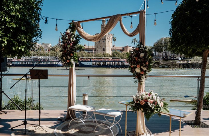 Altar de ceremonia civil con flores en la terraza frente al río